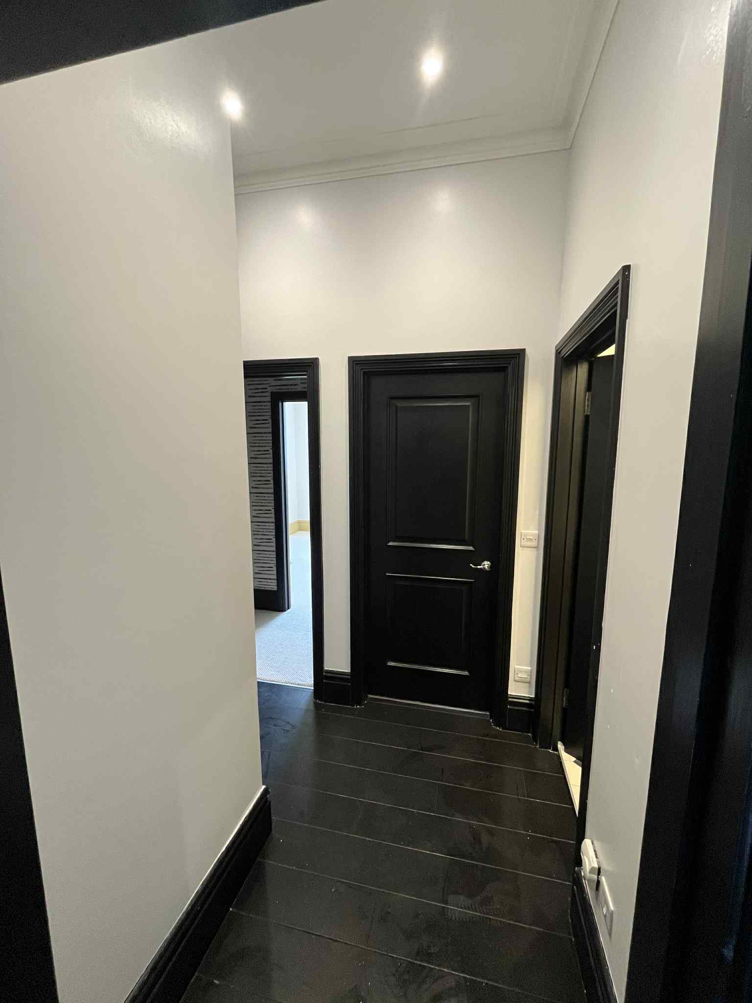 Freshly painted light hallway with black doors after decorating