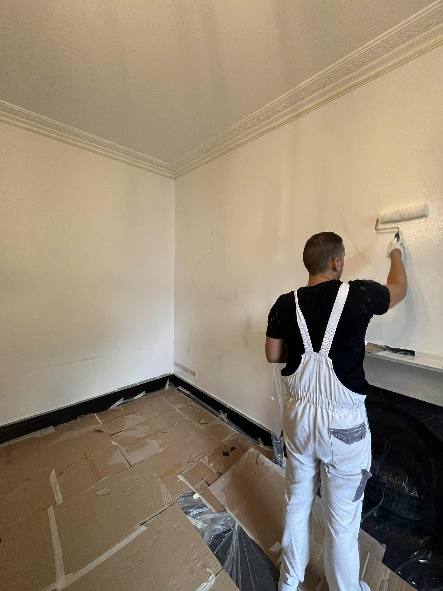 Painter applying a fresh coat in a period living room